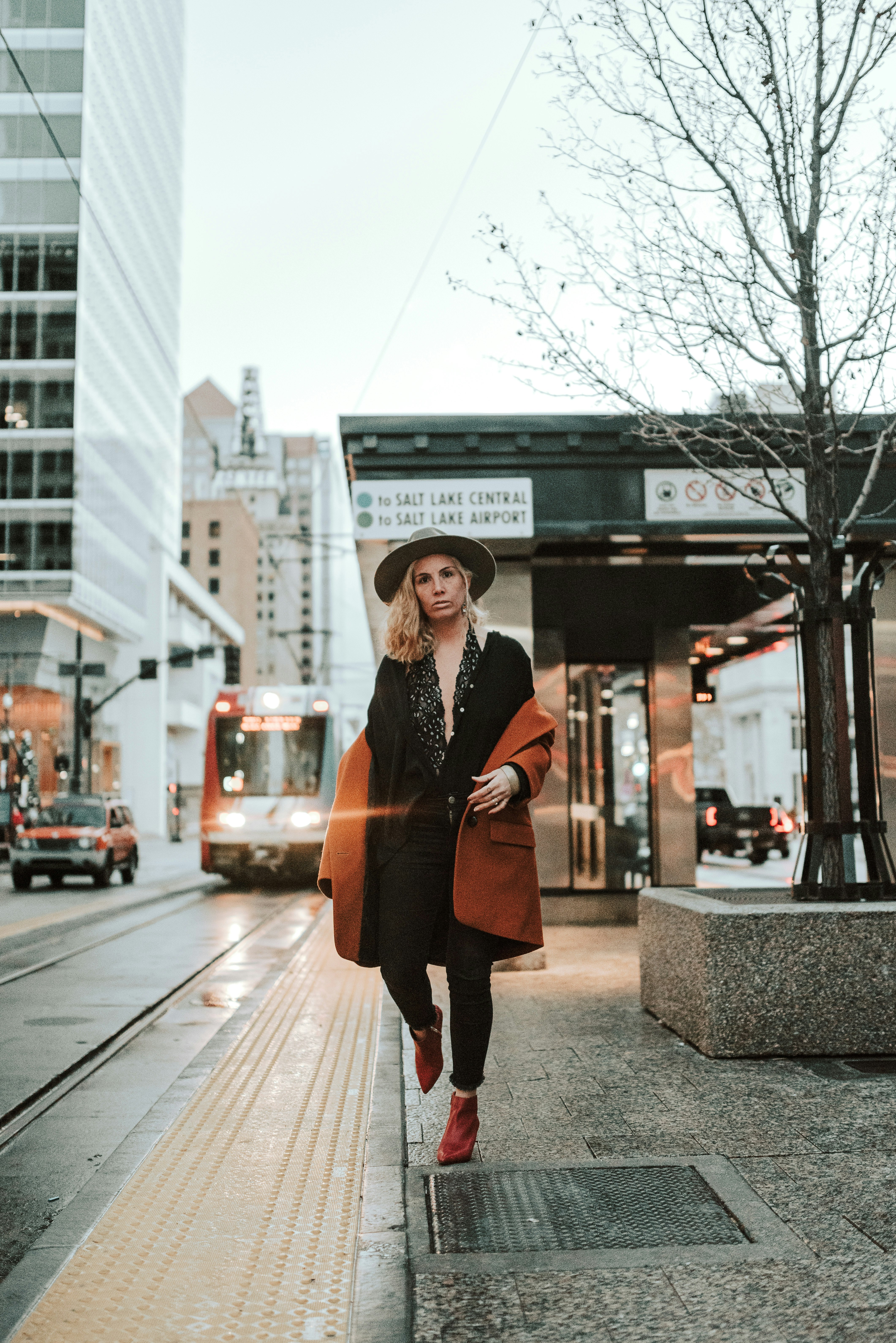 woman in black and brown coat standing on sidewalk during daytime